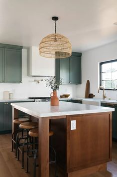 a kitchen with green cabinets and an island in front of the countertop, is shown