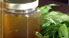 a jar filled with liquid sitting on top of a table next to some green leaves