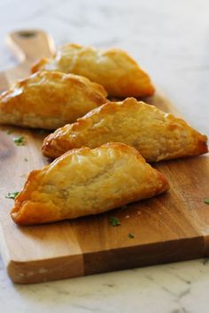 three pastries sitting on top of a wooden cutting board