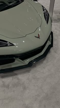 the front end of a green sports car on display at an auto show or showroom