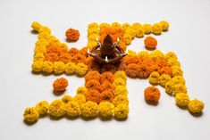 the letters are made out of orange and yellow flowers on a white surface with a small bird perched on top