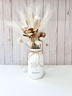 a white mason jar with dried flowers in it