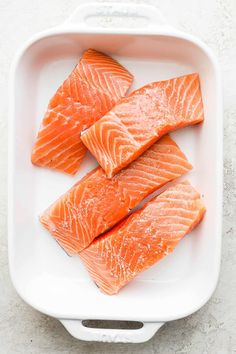 four pieces of salmon in a white dish