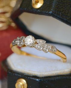 a close up of a ring in a box with gold and diamonds on it's side