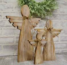 two wooden angel figurines sitting next to each other in front of a brick wall