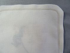 a close up of a white blanket on a gray surface with an animal drawn on it