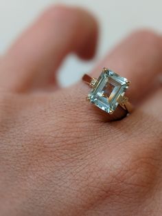 a woman's hand with a ring that has an aquamarine colored stone in it