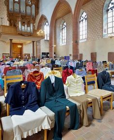 rows of tables and chairs with cloths on them in a large room filled with windows