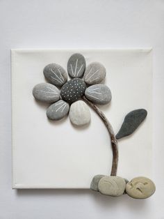 a white square with some rocks and a flower on it