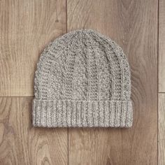 a gray knitted beanie sitting on top of a wooden floor