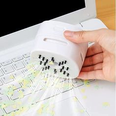 a hand is sprinkling something on top of a laptop keyboard with yellow and white stickers