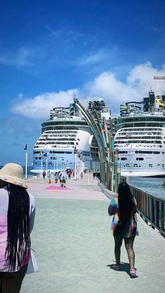 two women standing on a pier looking at cruise ships