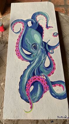 an octopus is painted on a piece of white paper with pink and blue tentacles in the center