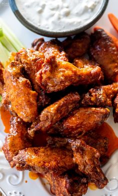 chicken wings with carrots, celery and ranch dressing on a white plate