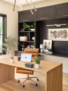 a desk with a laptop on it in front of a bookcase and window,