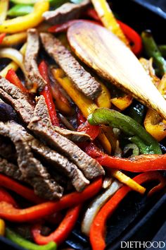 steak and peppers in a skillet with a wooden spoon on the side, ready to be eaten