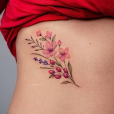 a woman's stomach with pink flowers and leaves on the side, behind her belly