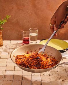 a person is cooking spaghetti in a pan