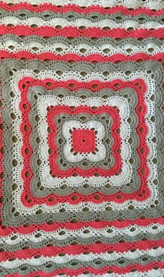 a crocheted blanket with red and gray squares on it, in the shape of square