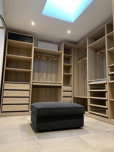 a large walk in closet with lots of shelves and drawers on each side, including a footstool