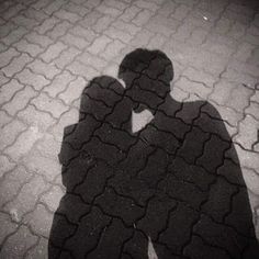 the shadow of a man and woman standing next to each other on cobblestone pavement