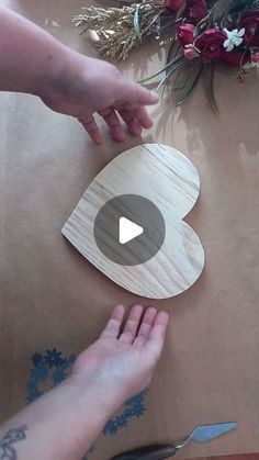 someone is cutting out a wooden heart with scissors