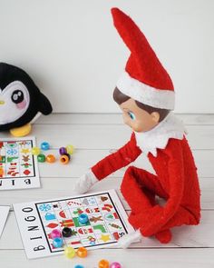 an elf is sitting on the floor next to a penguin and playing with candy candies