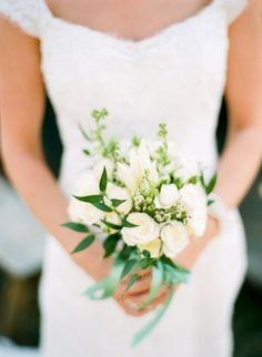 a bride holding a bouquet of white flowers