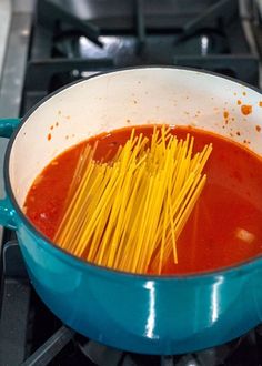 spaghetti being cooked in a blue pot on the stove