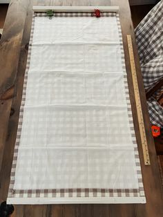 a piece of cloth is being laid out on a table with a ruler and tape