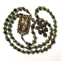 Vintage Style Catholic rosary beads, made with natural green jade stone, Pardon Crucifix with Side Medals, Our Lady of Perpetual Help centrepiece picture medal and a small Our Lady Miraculous side medal. This beautiful handmade Catholic rosary is crafted using 8mm natural green jade stone beads. The rosary features Pardon Crucifix adorned with attached Miraculous Medals and Saint Benedict Medal, complemented by Our Lady of Perpetual Help centrepiece picture medal and a small Our Lady Miraculous side medal. Key Features: *Crucifix: Brass, traditional, and beautifully detailed Pardon Crucifix with attached Miraculous Medals and Saint Benedict Medal. Made in Italy. 5.8cm. The text on the reverse reads: "Behold this heart which has so loved men - Father forgive them."  *Centrepiece Medal: Our Green Spiritual Beads For Healing, Green Bohemian Necklace With 8mm Beads, Green Oval Beads Necklace In Spiritual Style, Green Oval Beaded Jewelry 8mm, Bohemian Beaded Rosary For Healing, Green Oval Beads Necklace With Spiritual Style, Green Oval Beads Spiritual Necklace, Green Gemstone Beads For Gifts, Spiritual Green Necklace With Oval Beads