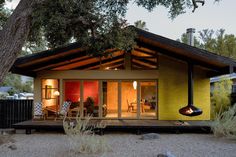 a small yellow and red house sitting under a tree