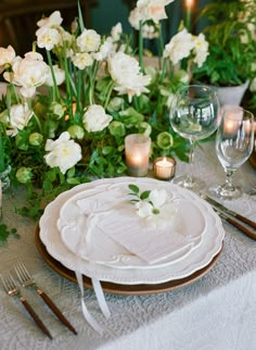 the table is set with white flowers and place settings for an elegant dinner or reception