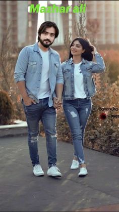 a man and woman are walking together in the city, holding hands while looking at each other