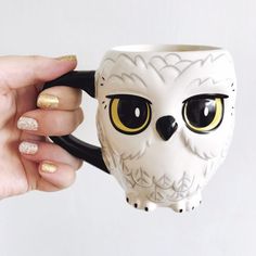 a hand holding a coffee mug with an owl face painted on the front and sides