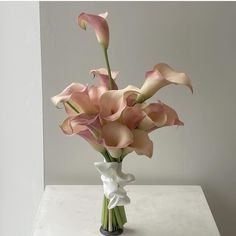 a vase filled with pink and white flowers on top of a table next to a wall