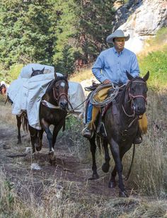 two men are riding horses with blankets on their backs and one man is walking behind them