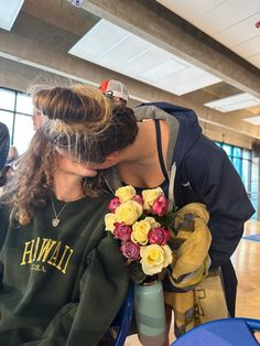 a woman holding a bouquet of flowers in front of her face while sitting on a chair