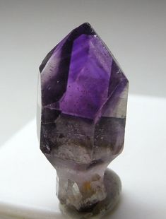 an amethorate with purple and grey colors on it's side sitting on a white surface