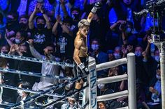 a man standing on top of a wrestling ring holding his hand up in the air