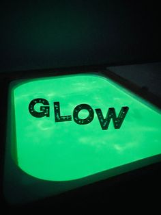 the glow sign is glowing green in the dark, with black lettering on it that says glow