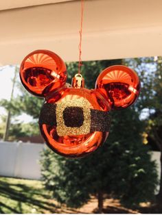 a mickey mouse ornament hanging from the side of a house with trees in the background