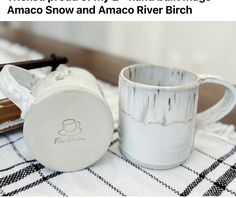 two white mugs sitting next to each other on a table