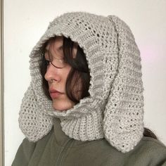 a woman wearing a knitted hoodie and looking off into the distance with her eyes closed