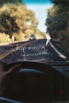 a car driving down a road with the words keep moving forward written on the windshield