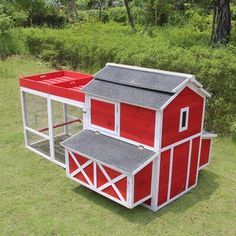 a red and white chicken coop sitting in the grass