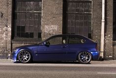 a blue car parked in front of a brick building