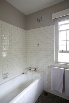 a bathroom with white tile walls and flooring next to a bathtub in the corner