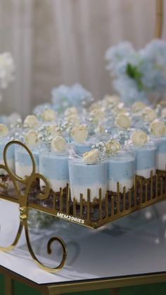 there are many candles on the table with blue flowers in them and one candle is gold