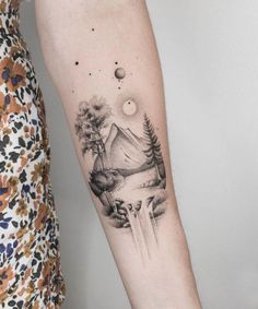 a woman's arm with a mountain and trees tattoo on the left inner forearm